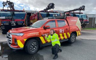 Airfield Operations Technician at Cardiff Airport demonstrating AVIX Handheld Laser Bird Deterrent in front of emergency response vehicles on the airfield