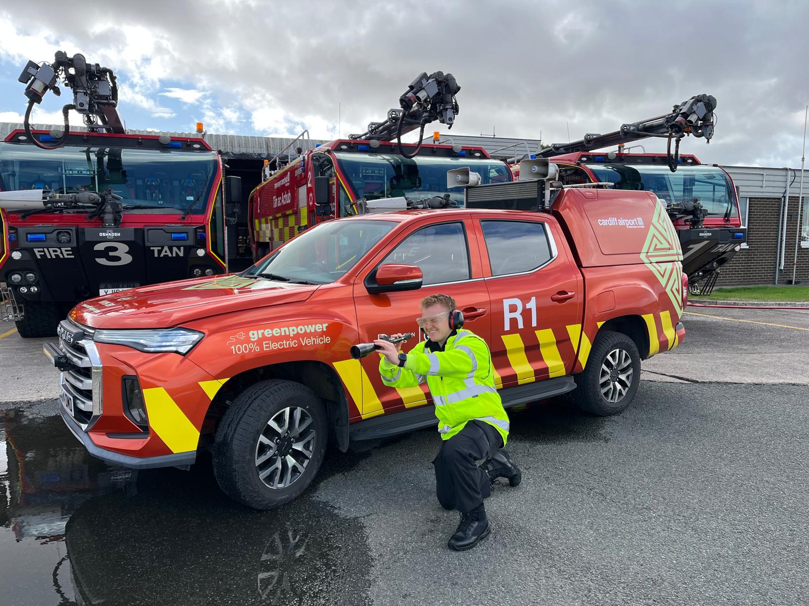 Airfield Operations Technician at Cardiff Airport demonstrating AVIX Handheld Laser Bird Deterrent in front of emergency response vehicles on the airfield